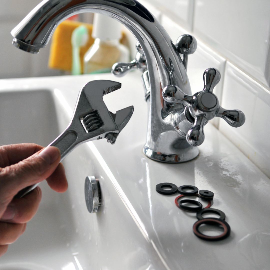 An image of a wrench next to a sink faucet.