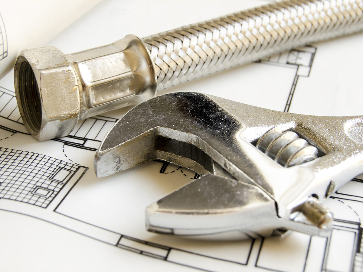 An image of plumbing tools and a house blueprint. 